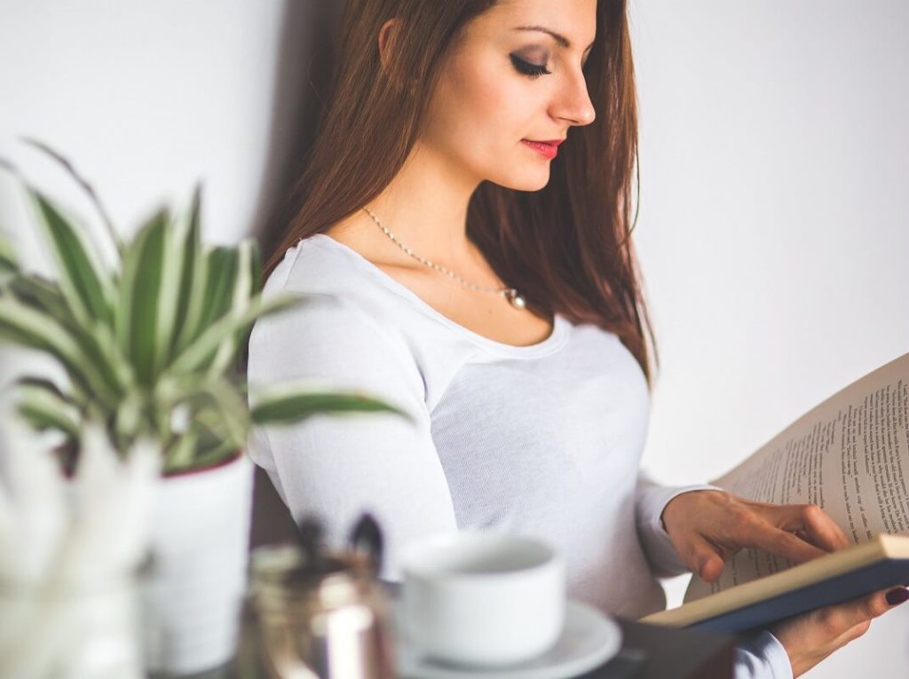 Kaunis nainen lukee kirjaa tyytyväisenä ratkaisuunsa yhdistää lainansa