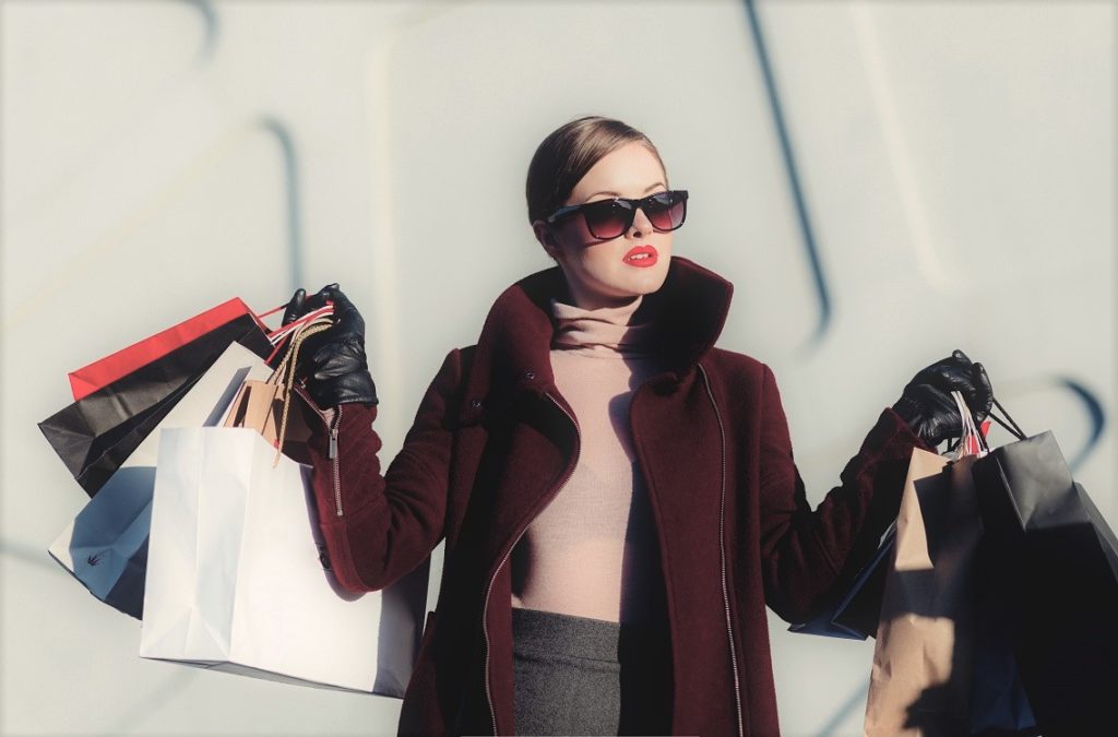 Kaunis nuori nainen kantaa kauppakasseissa tekemiään ostoksia.